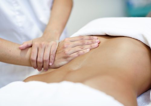 Hands massaging female abdomen.Therapist applying pressure on belly. Woman receiving massage at spa salon